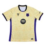 Camisa Barcelona II 25/26 Masculina Torcedor – modelo reserva da temporada 2025-2026, nas cores amarelo-dourado, preto e violeta, inspirada em Kobe Bryant com detalhes exclusivos da Coleção Mamba Barcelona.