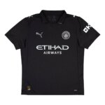 Camisa Manchester City preta modelo torcedor 25/26 com escudo em prata metálica e gola tradicional branca.
