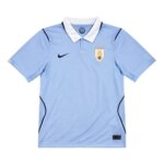 Camisa titular do Uruguai 2026, azul celeste, com gola polo branca e escudo AUF com quatro estrelas.